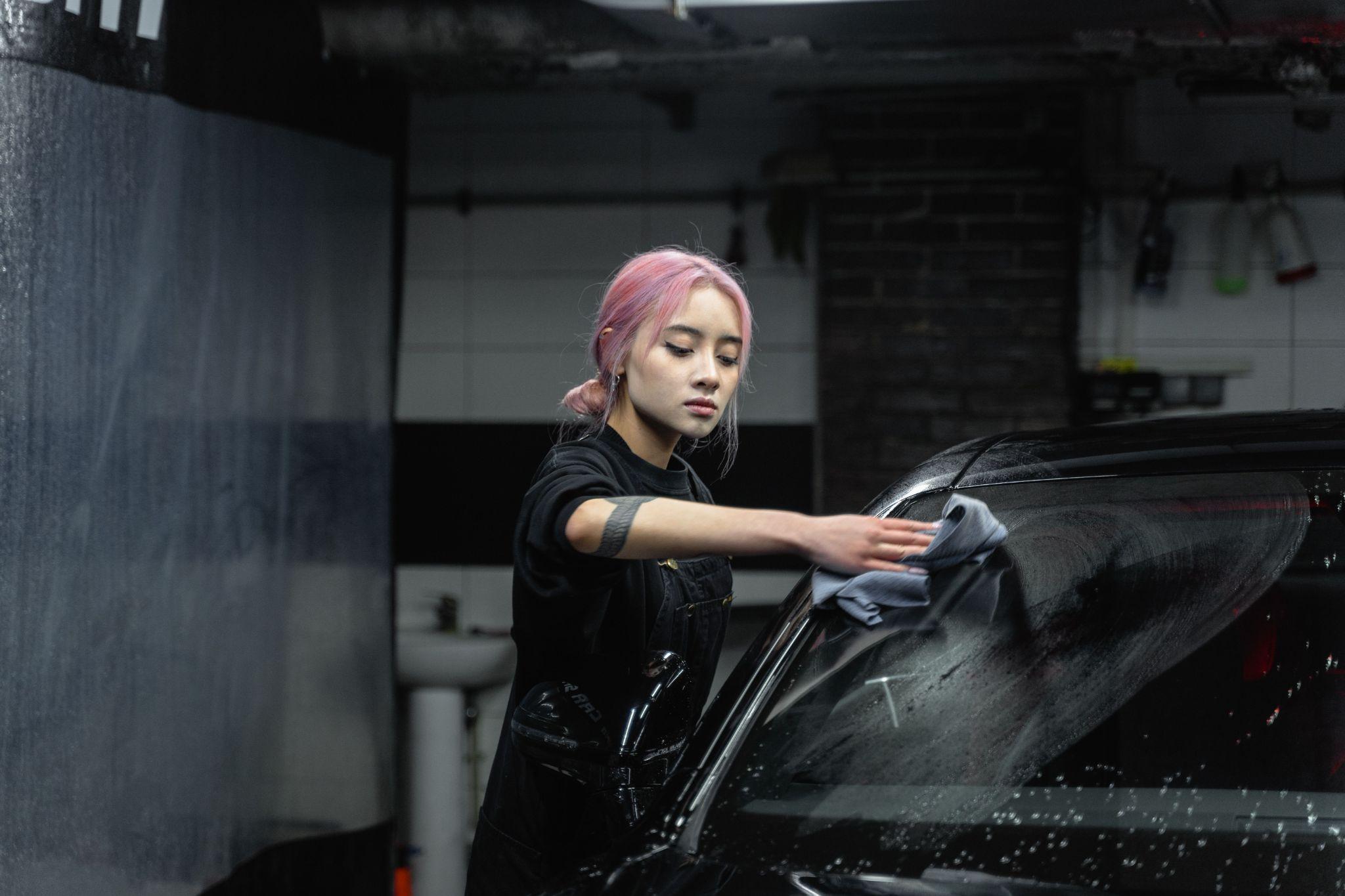 Cleaning a car window with a soft microfiber cloth to protect the tint