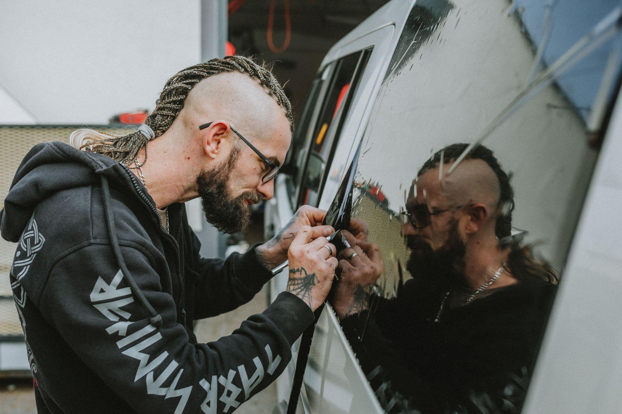 Professional applying window tint film to a car window