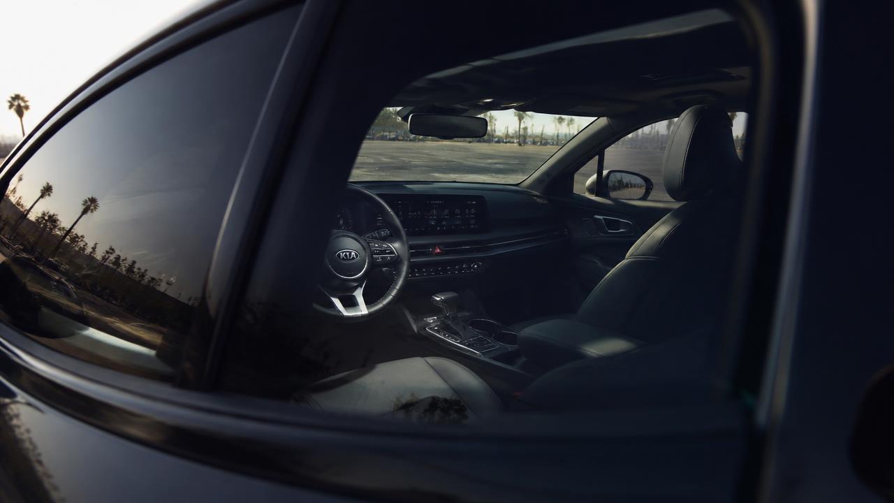 Cool, shaded car cabin seen through a tinted side window while parked on an open California asphalt lot in full sun